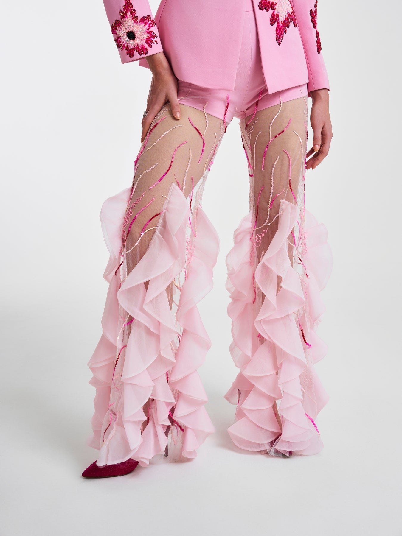 Close-up of pink ruffled trousers showcasing intricate embroidery and flowing sheer fabric